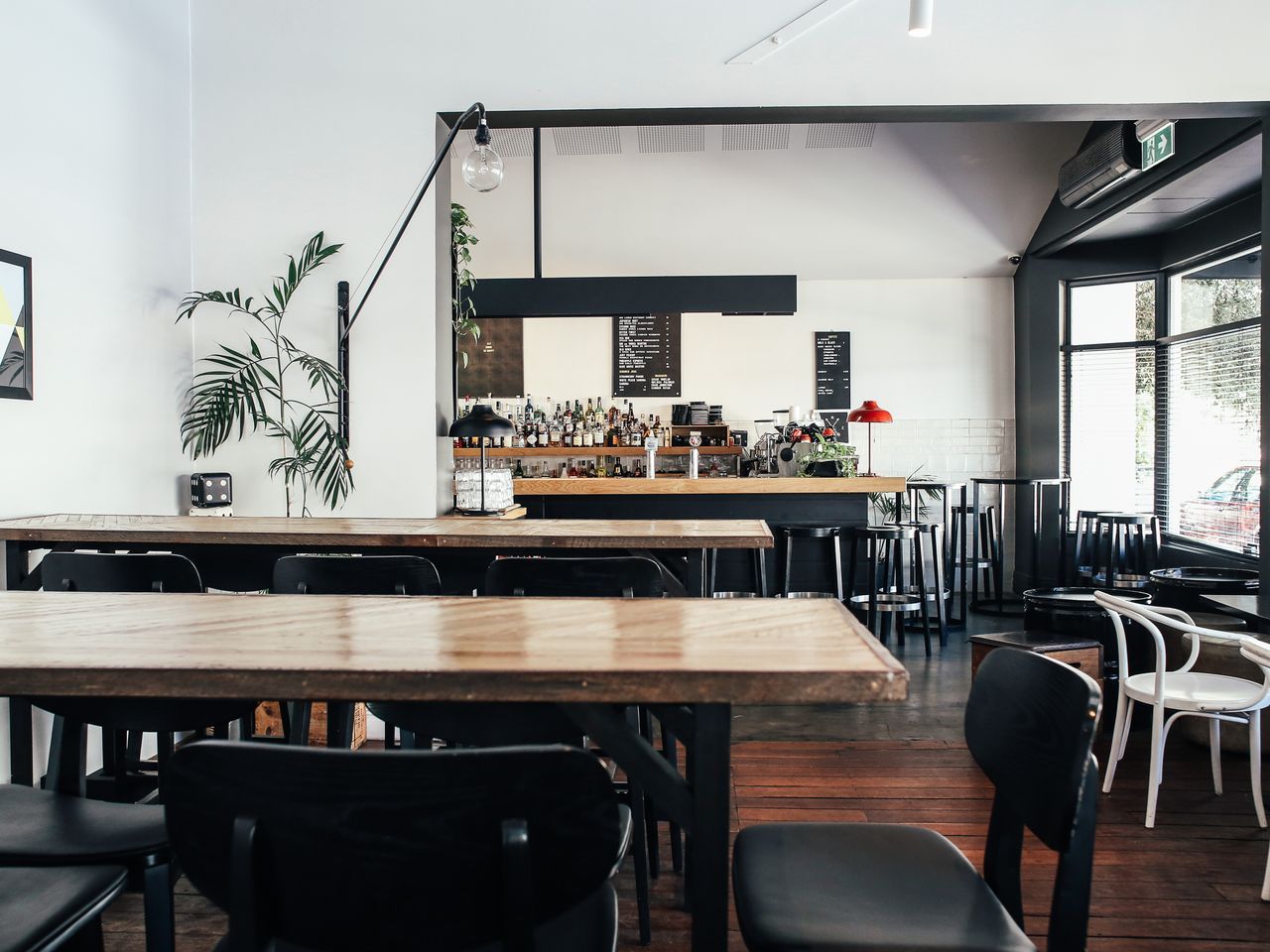 Airy café room with light wood tables and chairs by a bright window